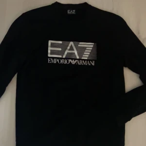 Svart långärmad tröja från Emporio Armani - Säljer en svart långärmad tröja från Emporio Armani med EA7 på bröstet. Tröjan är i bra skick och använts fåtal gånger.