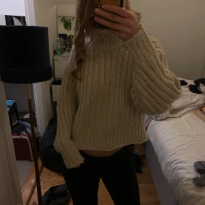 Beige stickad tröja - Säljer en mysig beige stickad tröja med ribbad design. Tröjan har långa ärmar och en något croppad passform, perfekt för kyliga dagar. Den är både stilren och bekväm.