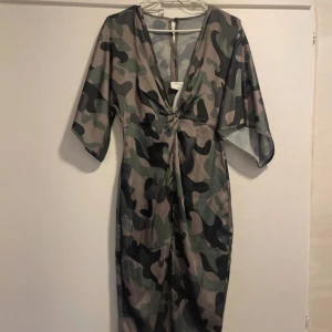 Klänning  från NA-KD - Snygg  klänning från NA-KD i storlek 34. Den har en djup v-ringning och trekvartsärmar. Klänningen är i ett mjukt och bekvämt material.