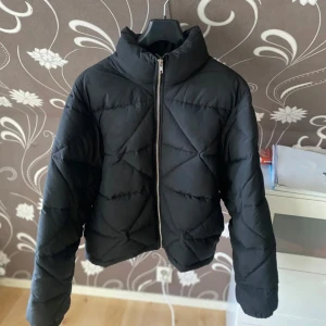 Pufferjacka från Gina Tricot - Säljer en svart pufferjacka från Gina Tricot i storlek M. Jackan har en dragkedja framtill och är quiltad för extra värme. Perfekt för kyliga höst- och vinterdagar. Köpt föra vintern men har bara använt några gånger. Nypris 499kr
