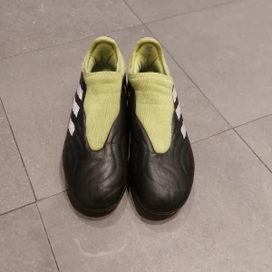 Adidas Copa fotbollsskor - Säljer ett par Adidas Copa fotbollsskor i svart och limegrön färg. Skorna har en stilren design med de klassiska tre ränderna på sidan. De är i bra skick och perfekta för fotbollsträning eller match. Skorna har en tight passform och är gjorda i syntetmaterial för bästa komfort och hållbarhet. Nypris 1200kr