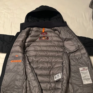Svart dunjacka från Parajumpers - Säljer en svart dunjacka från Parajumpers i väldigt  bra skick. Jackan har en quiltad design med dragkedja och en praktisk huva. Perfekt för kalla vinterdagar. Den har en snygg patch på ärmen och flera fickor för förvaring. Enda defekten som finns är att vänster sidoficka är sönder i blixtlåset men det är ingen svår fix för den som känner någon som kan fixa blixtlås. Nypris 5000, köptes in förra vintern. 