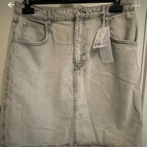 Grå jeanskjol från Perfect Jeans - Säljer en snygg grå jeanskjol från Perfect Jeans i storlek 44. Kjolen har en klassisk femficksdesign och är perfekt för både vardag och fest. Den är i nytt skick med etikett kvar. Passar perfekt till en avslappnad stil med sneakers eller klä upp med klackar.