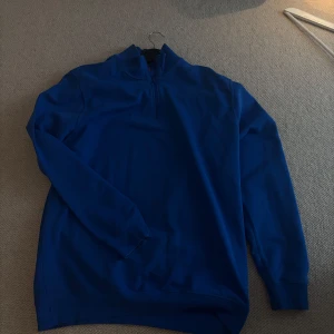Blå tröja med dragkedja - Säljer en snygg blå tröja med halv dragkedja. Tröjan har långa ärmar och en bekväm passform. Size L fits true to size