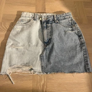 Tvåfärgad jeanskjol - Snygg tvåfärgad jeanskjol med slitna detaljer. Kjolen har en design med en ljus och en mörk del. Perfekt för i sommar och super fin!💕