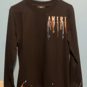 Amiri Tröja - Säljer en svart långärmad tröja från Amiri med coolt broderat mönster i flera färger. Perfekt för att ge din outfit en unik touch. Tröjan är helt ny aldrig använd, TAG FORTFARANDE KVAR. Passar S/M. Kontakta vid intresse