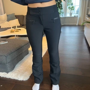 Svarta skidbyxor från 8848 - Säljer ett par svarta skidbyxor från 8848 i storlek 38 long. De har en tight passform med dragkedjor framtill och slitsar vid bensluten. Liten i storleken. Har vanligtvis 36 och dessa är i 38. Byxorna är i mycket bra skick. 