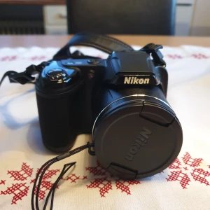 Kamera/väska - Den kamera heter Nikon, kamera model heter 28×OPTICAL ZOOM WIDE och  COOLPIX L340.Den som köper min kameran så med karmeraväskan 
