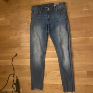 Blå skinny jeans från Crocker - Snygga blå skinny jeans från Crocker med en modern tvätt och fransiga benslut. Perfekta för en trendig look. De har en klassisk femficksdesign och knappgylf.