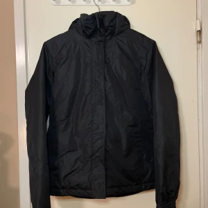 Svart jacka från Crivit - Säljer en svart jacka från Crivit med dragkedja och huva. Perfekt för kyligare dagar. Jackan har en stilren design och är tillverkad i syntetmaterial. Passar bra för både vardag och utomhusaktiviteter.