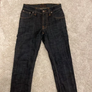 Mörkblå jeans från Nudie Jeans - säljer ett par nudie jeans i storleken w26 l32 i extremt fint skick! Priset är inte hugget i sten så kom med bud!