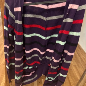 Randig kofta från Dr. Denim - Säljer en färgglad randig kofta från Dr. Denim i storlek S. Koftan har långa ärmar och ett mönster i lila, rosa, rött, svart,grått och grön . Perfekt för att liva upp garderoben med lite färg!