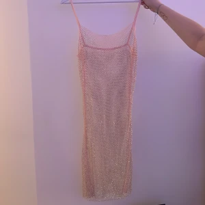 Glittrig nätklänning i rosa - Säljer en superfin glittrig nätklänning i rosa. Den är axelbandslös och har en tight passform som verkligen framhäver figuren. Perfekt för en kväll ute eller en speciell tillställning. ✨Köpt i mallorca & är oanvänd  ❤️