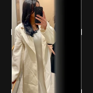 Vit kappa - Snygg vit kappa med klassisk design och långa ärmar. Perfekt för att ge en stilren look. Den har en elegant passform och är ett måste i garderoben för kyligare dagar.
