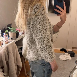 Grå tweedjacka med paljettdetaljer - Säljer en chic grå tweedjacka med vita kanter och paljettdetaljer på fickorna. Jackan har trekvartsärmar och en öppen design, perfekt för en stilren look. Passar bra till både jeans och kjol. Perfekt för höst och vår! Ja kan är i M men skulle säga att den mer är som en S