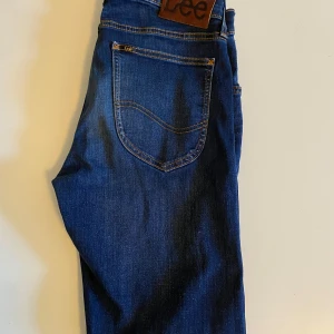 Mörkblå jeans från Lee - Snygga mörkblå jeans från Lee med klassisk femficksdesign. De har en normal passform och är perfekta för en avslappnad stil. Jeansens mörka tvätt ger en stilren look. Spotlek w29 L32