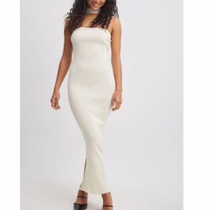 Vit ribbad klänning från NA-KD - Snygg vit ribbad klänning från NA-KD med en tight passform och slits. Klänningen är ärmlös och har en stilren design som passar perfekt för olika tillfällen. Tillverkad av återvunnet material för en hållbar stil. HELT NY MED LAPPEN KVAR🩷🩷