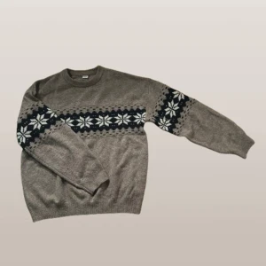 Brun stickad tröja - Säljer en mysig brun stickad tröja med ett vackert snöflingemönster i vitt och mörkblå färg. Tröjan har långa ärmar och rund halsringning, perfekt för kyliga dagar. Passar både till vardags och mysiga stunder hemma. 