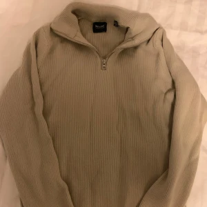 Beige ribbad tröja från Only & Sons - Säljer en stilren beige ribbad tröja från Only & Sons. Tröjan har en dragkedja vid halsen och långa ärmar, perfekt för kyligare dagar. Passar bra till både jeans och chinos.