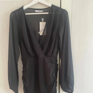 Svart omlottklänning från NA-KD - Svart omlottklänning från NA-KD med långa ärmar och v-ringad design. Oanvänd med lapp kvar!!