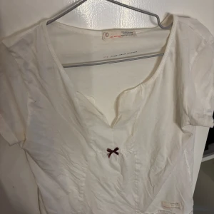 Vit topp från Odd Molly - Säljer en vit topp från Odd Molly med en liten röd rosett 