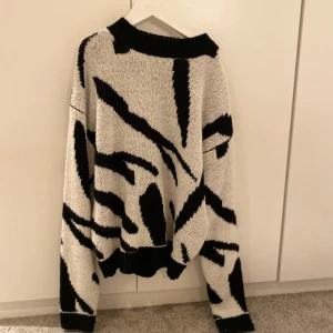 Svartvit stickad tröja från NA-KD🫶🏻 - Säljer en cool svartvit stickad tröja från NA-KD med ett unikt mönster. Tröjan har långa ärmar och en bekväm passform. Perfekt för att ge din outfit en trendig touch. Endast använd några få gånger🥰