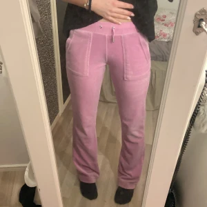 Rosa Juicy Couture - juicy couture rosa xxs. Snygga rosa mjukisbyxor med broderad logga på benet. Byxorna har en hög midja och raka ben. De är utrustade med snörning i midjan och har praktiska fickor både fram och bak. Ett av snöret har åkt in. 