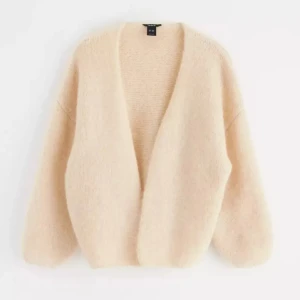 Beige fluffig kofta  - Mysig beige kofta från Lindex i ett fluffigt material. Den har en öppen design utan knappar och långa ärmar. 