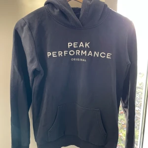 Hoodie från Peak Performance - Använd hoodie men i fint skick. Tror den är mörkt marinblå men ser svart ut i vissa ljus. Stl 160. 