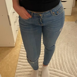 Blå zara jeans - Lågmidjade blå jeans med slitningar på knäna. Från zara.