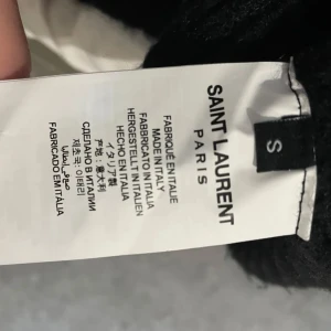 Svart tröja från Saint Laurent - Snygg svart tröja från Saint Laurent med vit logotyp på framsidan. Tröjan har långa ärmar och en rund halsringning. Perfekt för en stilren look.