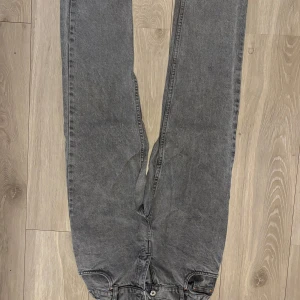 Grå jeansbyxor GRUNT  - Snygga grå jeansbyxor med en klassisk straight passform. Perfekta för en avslappnad stil. De har en midwaist design och är tillverkade i slitstarkt denim.