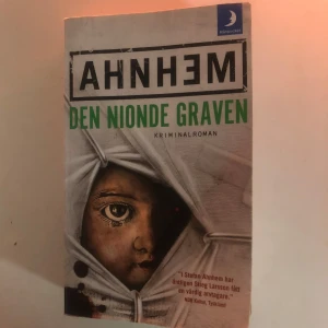 Den nionde graven - Säljer boken 'Den nionde graven' av Ahnhem, en kriminalroman utgiven av Månpocket. Omslaget visar ett barnansikte delvis dolt bakom en vit duk. Perfekt för dig som gillar spännande deckare.