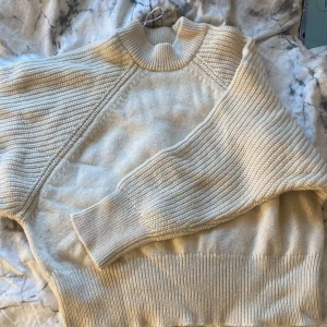 Beige stickad tröja - Säljer en mysig beige stickad tröja med ribbade detaljer. Tröjan har långa ärmar och en rund halsringning. Perfekt för kyliga dagar och enkel att matcha med olika outfits. Sälja på grund av att man inte använder längre 
