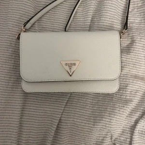 Vit axelväska från Guess - Snygg vit axelväska från Guess med justerbar rem . Knappt använd och jätte bra skick 