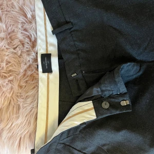 Svarta kostymbyxor från Five units  - Snygga svarta kostymbyxor från Five Units med en stilren design. Byxorna har en dragkedja och knapp framtill samt hällor för bälte. 