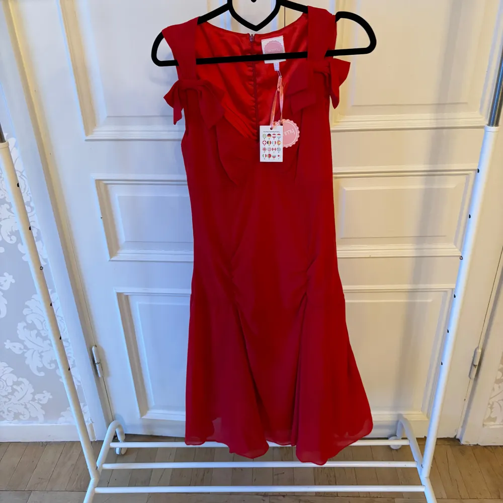 Jättefin röd klänning i skönt material med två fina rosetter. Storlek 38 Modellen på bilden är 173 cm och har storlek 38 i de flesta andra kläder. Aldrig använd. Vi har lagt ner vår klänningsbutik och säljer ut. Ny pris är 2000-3000kr. Mekot.