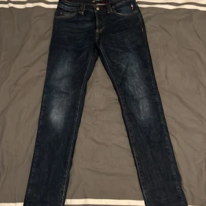 Mörkblå jeans från Philipp Plein - Snygga mörkblå jeans från Philipp Plein med en super straight fit. De har klassiska fem fickor och en knappgylf. Perfekta för en stilren look. Storlek 30/32. Skriv för funderingar. Pris kan diskuteras vid snabb affär.
