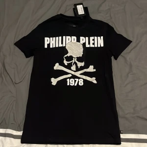 Svart t-shirt med dödskalle från Philipp Plein - Snygg svart t-shirt från Philipp Plein med en stor döskalle på framsidan, den är helt oanvänd, lapparna sitter fortfarande kvar. Skriv för funderingar. Pris kan diskuteras vid snabb affär.