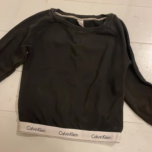 Svart tröja från Calvin Klein - Säljer en svart tröja från Calvin Klein med lång ärm och vit resårkant med logotyp. .