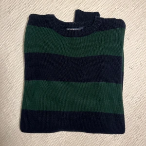 Randig stickad tröja Brandy Melville  - Säljer en mysig stickad tröja med breda ränder i grönt och svart. Perfekt för kyligare dagar med sin klassiska design och bekväma passform.