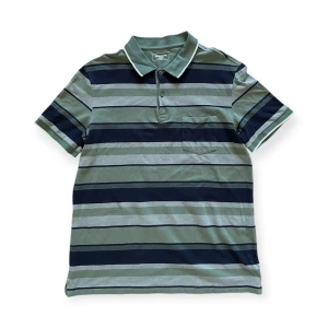 Grön randig pikétröja skjorta - En cool randig pikéskjorta med härliga 90-tals vibbar. I fint skick. Står storlek XL men skulle säga M/L. För mått kontakta mig!!