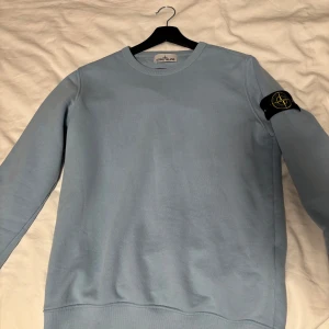 Ljusblå tröja från Stone Island - Säljer denna feta tröja från Stone Island🪨🏝️.  Skick 9/10. Tröjan har en klassisk passform som passar både S och M & sitter som en smäck✅riktigt skön och snygg 🔥priset är inte skrivet i sten💵 vid fler frågor kom DM
