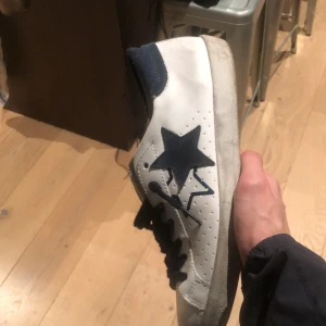 Vita sneakers 2star - Snygga vita sneakers med en svart stjärna på sidan och svarta snören. Perfekta för en avslappnad stil. Märket är 2Star. Stl 43.