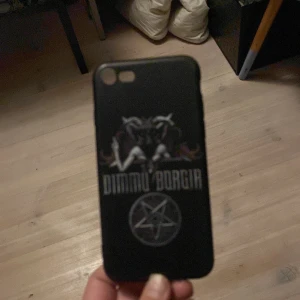 Svart mobilskal med Dimmu Borgir-design - Snyggt svart mobilskal med Dimmu Borgir-logga och pentagram. Perfekt för fans av bandet som vill ge sin telefon en unik och personlig touch. Skalet har en stilren design med mörka toner.