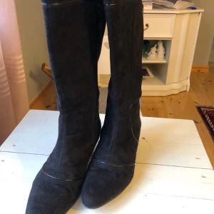 Svarta stövlar med klack - Snygga svarta stövlar i mocka med en diskret klack och spetsig tå. Perfekta för höst och vinter, dessa stövlar har en stilren design som passar till många olika outfits.