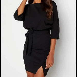 Svart klänning från Bubbleroom - Elegant svart klänning från Bubbleroom med knytband i midjan, liten slith vid högra sidan och trekvartsärmar. Perfekt för en stilren look med en smickrande passform. Klänningen har en diskret dragkedja i ryggen. Klänningen har endast använts  gång och är i bra skick. Den är i storlek 36. Originalpris mellan 50-60€. Kontakta för mer information🫶🏻