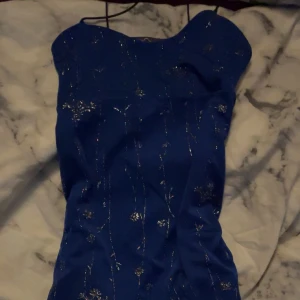 Blå glittrig klänning från Blooms - Snygg blå klänning med glittriga detaljer från Blooms. Den har smala axelband. 
