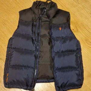 Polo Ralph Lauren dunväst  - Perfekt julklapp i nyskick. Mycket varm supersnygg puffer väst  i midnattsblått/svart. Storlek M. Modellen är 182 cm och väger 74 kg. 