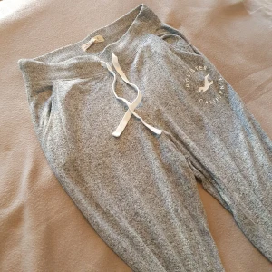 Grå mjukisbyxor från Hollister - Säljer ett par grå byxor från Hollister i sååå mysigt tyg! 💛 Snörning i midjan, logga på benet och fickor!!! 😍 Stretchiga och snörning så passar XS-M. Använda men fortfarande bra skick, hör av er vid frågor! 
